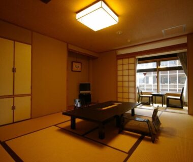 Traditional tatami room with low table, zabuton cushions and shoji screens at Kamogawakan in Kyoto