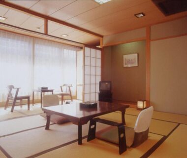 Traditional tatami room with low table, zaisu chairs, shoji screens and seating by windows at Kamogawakan in Kyoto