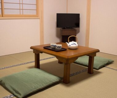 Tatami room with low wooden table, cushions, shoji screen and TV at Kamoya Ryokan Kyoto