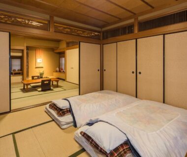 Traditional tatami room with futon bedding, low table and sliding fusuma doors at Kamuroan Kyoto