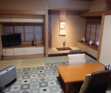 Traditional tatami room with low table, shoji screens, tokonoma alcove and TV at Kamuroan, Kyoto
