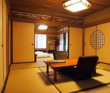 Traditional tatami room with low table, zabuton chairs and futon visible through sliding fusuma at Kamuroan, Kyoto