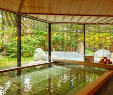 Wooden indoor onsen with large windows overlooking a leafy garden at Kanaya Hotel Kinugawa, Tochigi
