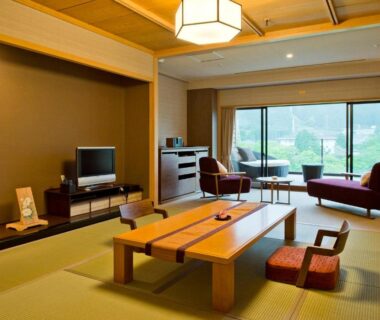 Tatami room with low table, cushions and lounge seating overlooking greenery at Kanaya Hotel Kinugawa, Tochigi