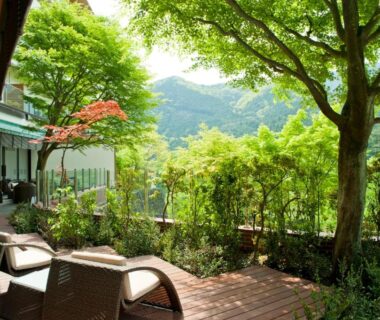 Wooden terrace with lounge chairs overlooking green hillside at Kanaya Hotel Kinugawa in Tochigi