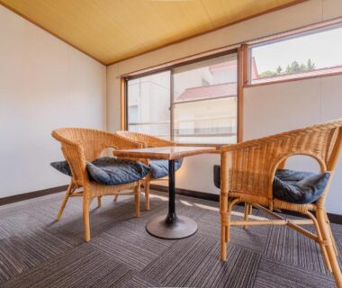 Wicker chairs and round table by low windows in Kaneki Hotel seating area, Nagano