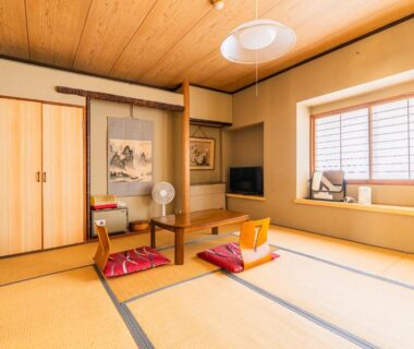 Traditional tatami room with low table, zabuton cushions, shoji window and tokonoma at Kaneki Hotel, Nagano