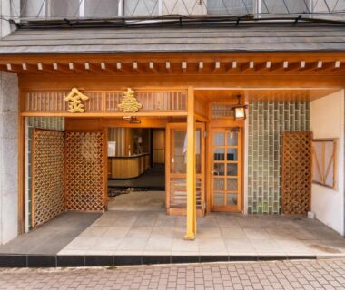Traditional wooden entrance with lattice panels and glass doors at Kaneki Hotel in Nagano, Chūbu
