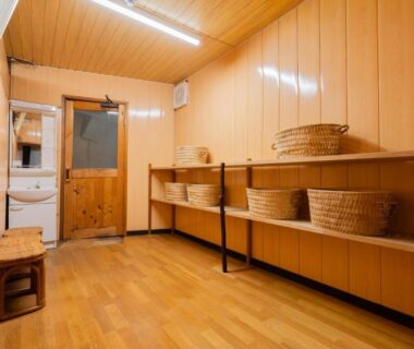 Wood-paneled changing room with wicker baskets and bench at Kaneki Hotel, Nagano, Chubu, Japan