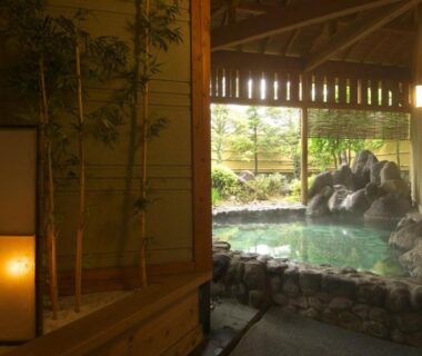 Stone onsen bath overlooking garden with bamboo screen and wooden lantern at Kanemidori in Gunma Kantō