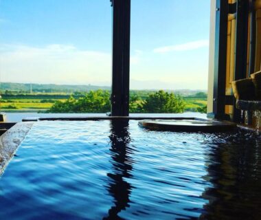 Wooden onsen bath facing expansive Hokkaidō countryside through large window