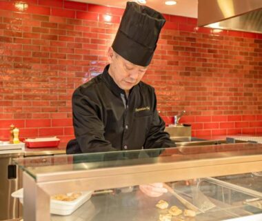 Chef in black uniform cooking at counter with red tile wall at Kangetsuen Hokkaidō ryokan