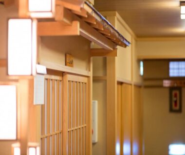 Warm wooden corridor with shoji doors and lantern lighting inside Kanko Ryokan Kuboji in Nara