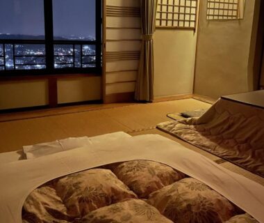 Traditional tatami room with futon bedding, shoji screens and night city view at Kanko Ryokan Yamato in Nara
