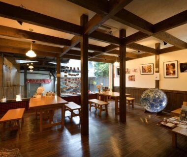 Wood-beamed lounge with wooden tables, globe, brochures and warm lighting at Kannawa Yunoka in Oita, Kyushu