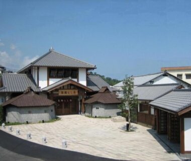 Paved courtyard and tiled roof buildings of Kannawaso in Ōita, Kyūshū under clear blue sky