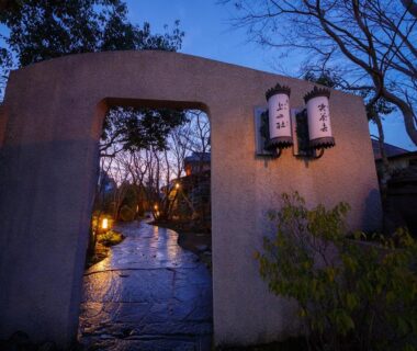 Evening lit stone path through gateway with lanterns at Kannomori in Ōita, Kyūshū