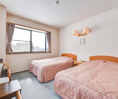 Twin beds with pink bedspreads, window view and simple wooden furniture at Kanoe, Nagano