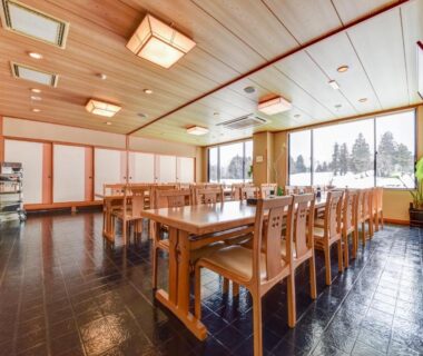 Spacious wooden dining room at Kanoe with shoji screens and large windows overlooking trees in Nagano