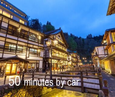 Evening lit wooden ryokan buildings along canal with bridge, Kansyokan, Yamagata Tōhoku Japan