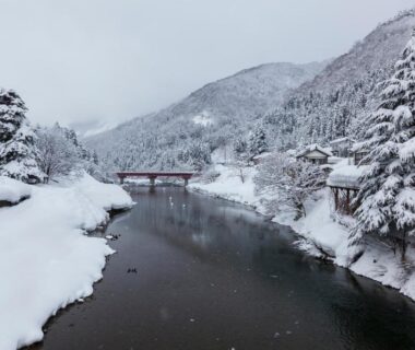 Snow-lined river with red bridge near Kansyokan in Yamagata, Tōhoku mountains