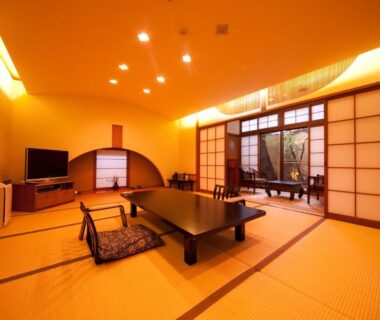 Spacious tatami room with low table, zabuton cushions and shoji screens at Kappo Ryokan Kannawa Bettei in Ōita