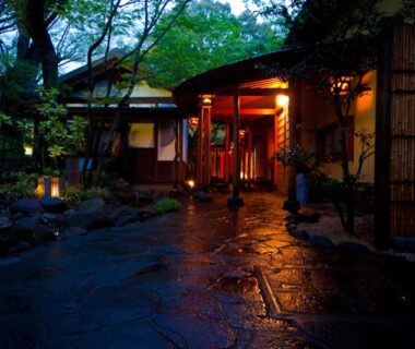 Wet stone path with lanterns leading to wooden entrance at Kappo Ryokan Kannawa Bettei Ōita