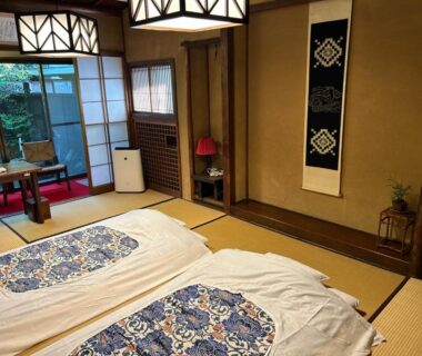 Traditional tatami room with futons, shoji screens, low table by window and hanging scroll at Kappo Ryokan Uoichi in Shizuoka