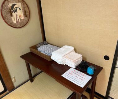 Folded linens and towels on wooden table in tatami room with shoji doors at Kappo Ryokan Uoichi Shizuoka