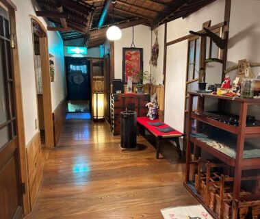 Wooden interior corridor with shoji doors, decorative shelves and lantern lighting at Kappo Ryokan Uoichi, Shizuoka