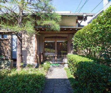 Stone path leading to wooden entrance with trimmed hedges at Kappo Ryokan Yumesaki in Oita