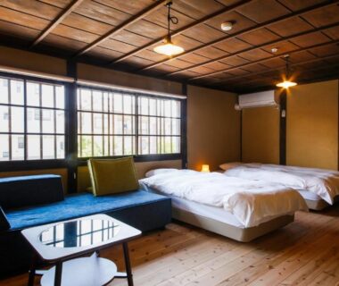 Low beds, sofa, wooden ceiling and lattice windows at Kariya Ryokan Q in Hyōgo, Kansai