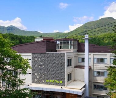 Multi-story ryokan building with trees and mountain backdrop at Karurusu Onsen Yumoto Orofuresou, Hokkaidō