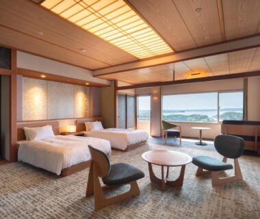 Twin beds, low table and seating with large window overlooking the bay at Kashikojima Hojoen