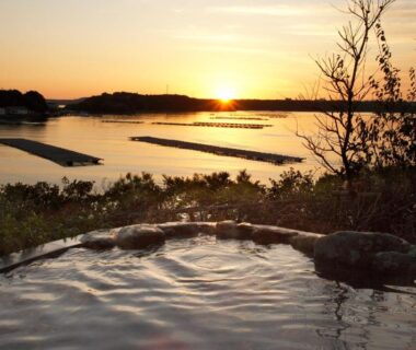 Outdoor onsen bath overlooking a coastal bay at sunset, Kashikojima Hojoen, Mie prefecture