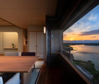 Tatami dining room with wooden table and large window overlooking bay at sunset Kashikojima Hojoen Mie