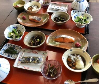 Assorted Japanese breakfast dishes with salmon, rice, pickles, miso and small bowls on wooden table at Kashiwaya Gassan Yamagata