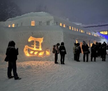 Illuminated snow sculptures and visitors outside Kashiwaya Gassan in Tōhoku Yamagata at dusk