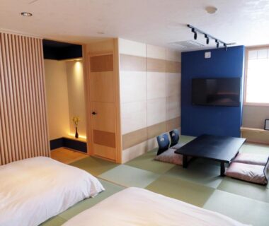 Room with tatami flooring, two beds, low table and floor cushions at Kashoutei Hanaya Hokkaidō