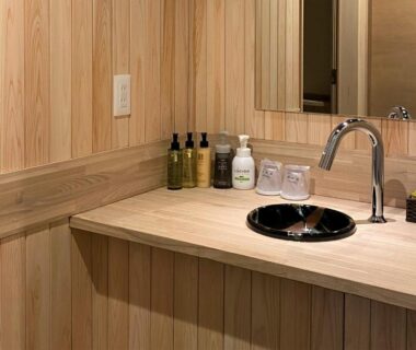 Wood-paneled washbasin area with black sink and toiletries at Kashoutei Hanaya in Hokkaido