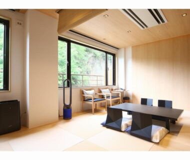 Bright tatami room with low table, floor cushions and large window overlooking greenery at Kashoutei Hanaya Hokkaidō