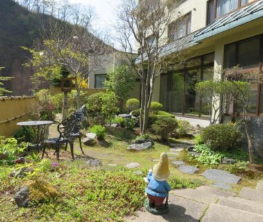 Courtyard garden with stone path, iron bench, moss and small statue at Kashoutei Hanaya Hokkaidō
