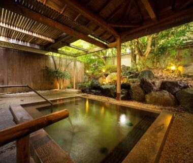 Wooden covered onsen bath beside rock garden at Kasuga Hotel Nara