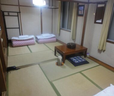 Traditional tatami room with two futons, low table and cushions at Kasuga Ryokan in Hiroshima