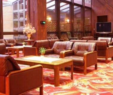 Wood-paneled lounge with upholstered sofas and low tables at Kasugai View Hotel in Yamanashi, Chūbu, Japan