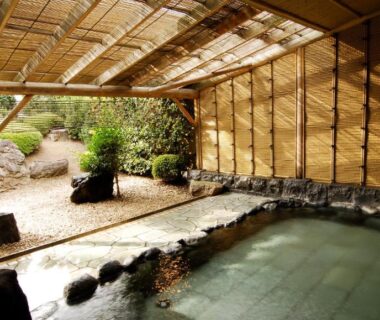 Stone-lined covered onsen bath with bamboo screen and garden at Kasugai View Hotel, Yamanashi