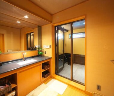 Indoor wash area with sink, mirror and wooden soaking tub behind glass at Kasuitei Ooya, Yamanashi