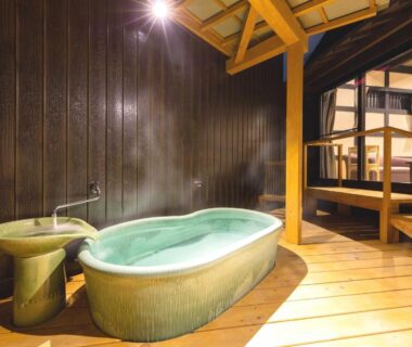 Ceramic onsen tub on wooden floor with exposed beams and open railing at Katsuragi Onsen Happuu No Yu Wakayama
