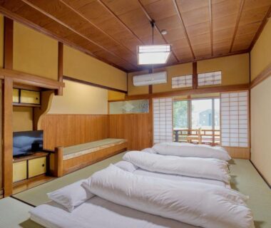 Traditional tatami room with futon bedding, shoji screens, wooden interior and low table at Katsuzakikan in Ishikawa