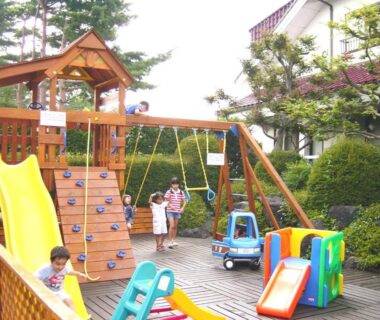 Children on wooden play structure and slide at Kawaguchiko Lakeside Hotel outdoor area, Yamanashi